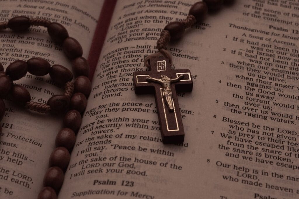 Home A rosary beads and crucifix resting on an open Bible displaying Psalms.